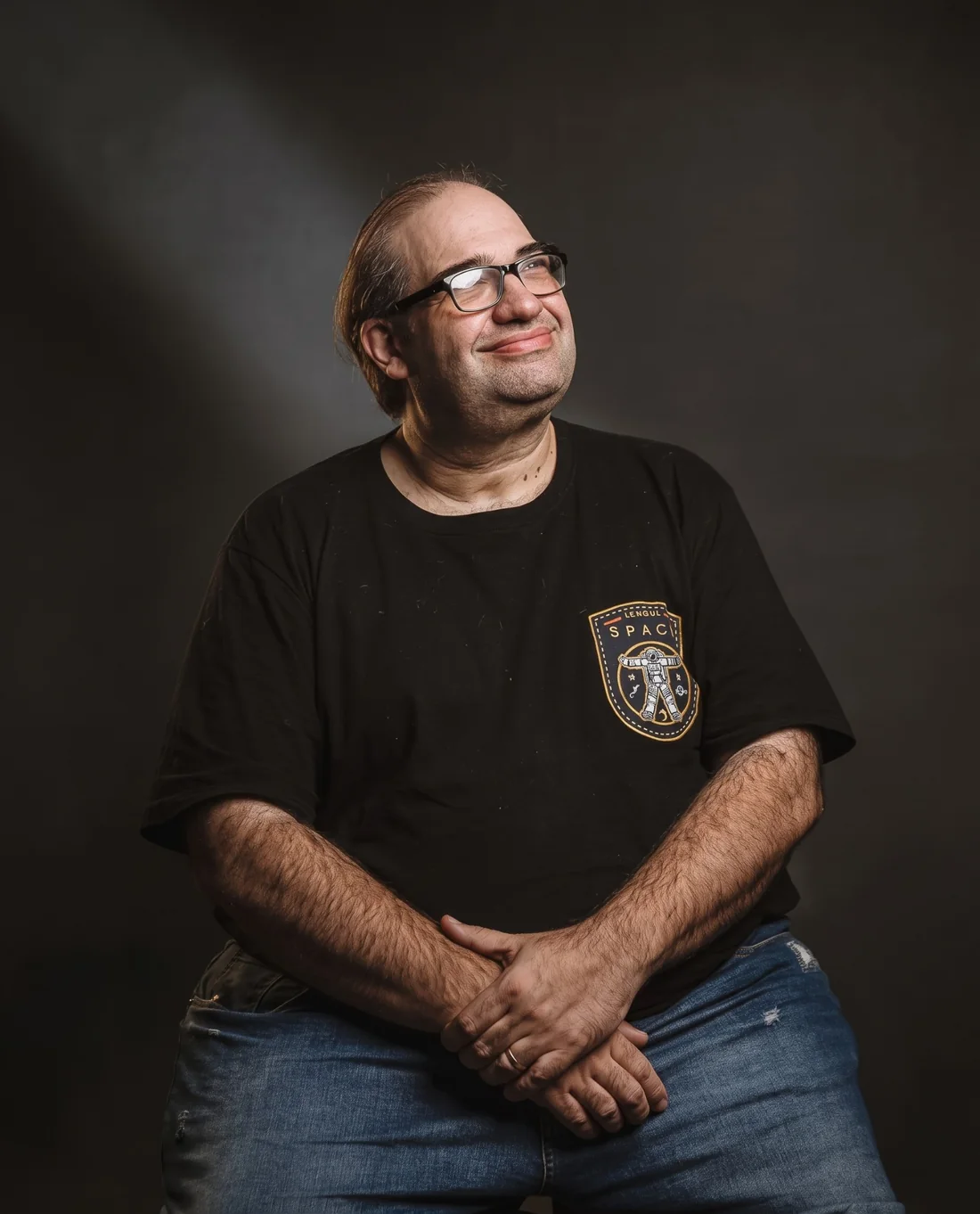 Sérgio Sacani sorrindo, olhando para cima, com a camiseta do patch SPACE