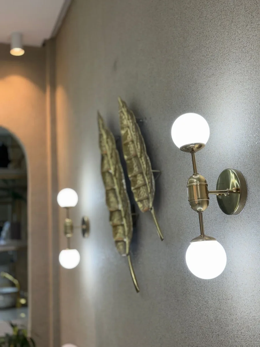 Detalhe das arandelas e das folhas douradas na parede da recepção